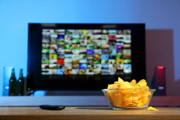istock Bowl of chips and TV remote control on table indoors. Space for text 1428733323