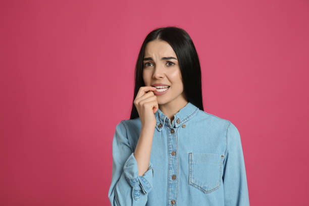 istock Young woman biting her nails on pink background. Space for text 1428734189