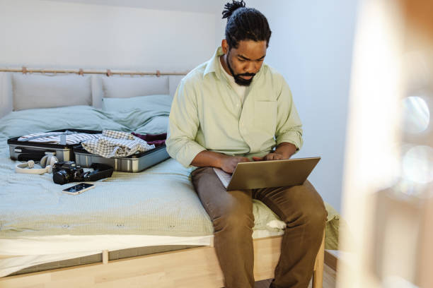 istock African-American man packing for a trip and checking mail on laptop 1428735165