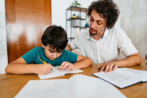 Young father helping his son with homework at home.