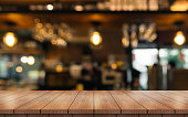 ぼかしレストランの背景にライトボケと空の木製のテーブルトップ。