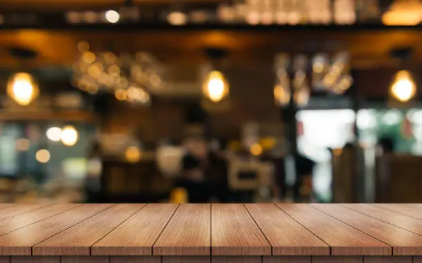 Photo of Empty wooden table top with lights bokeh on blur restaurant background.