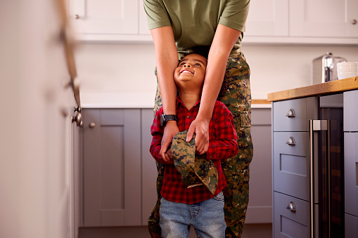 Close Up Of American Army Mother In Uniform Home On Leave With Son Holding Her Cap In Family Kitchen