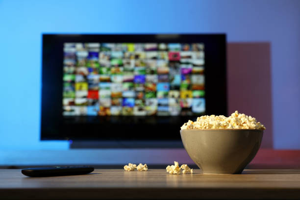 istock Bowl of popcorn and TV remote control on table indoors. Space for text 1428743891
