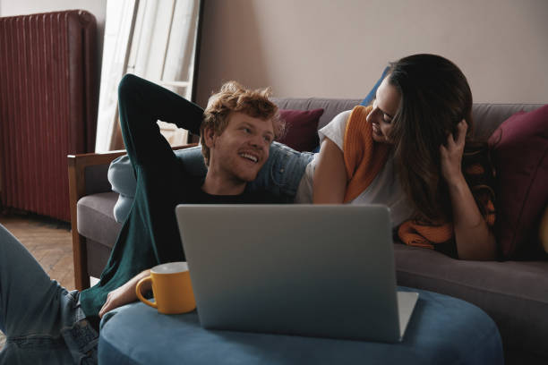 istock Happy young couple using laptop while relaxing at home together 1428747001