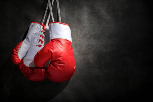 guantes de boxeo colgados en la pared con fondo gris grunge y espacio de copia - boxing ring combative sport fighting conflict fotografías e imágenes de stock