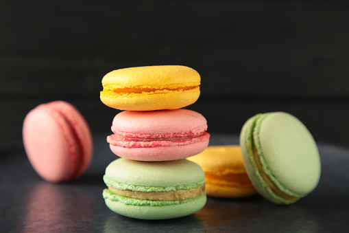 Colorful macarons cakes on dark background. Small French cakes. Sweet and colorful french macaroons. Top view