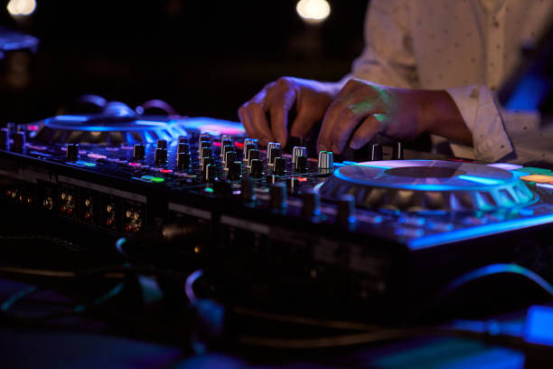 an unrecognizable person playing music at a party from a mixing console stock photo