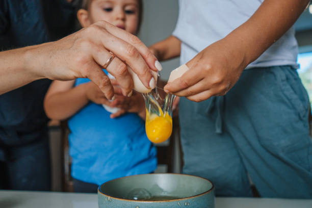 istock Mother hands breaking eggs in bowl with her two children while making breakfast on table. Unaltered, family, togetherness, childhood, food, preparation, learning, lifestyle and home. Parent, child. People lifestyle. 1428757476