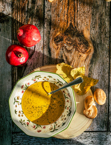 호박 수프와 버섯이 든 접시의 윗모습, 두 개의 석류가 이미지를 장식합니다. 나무 배경, 따뜻한 색상. - pumpkin soup soup cup pumpkin 뉴스 사진 이미지