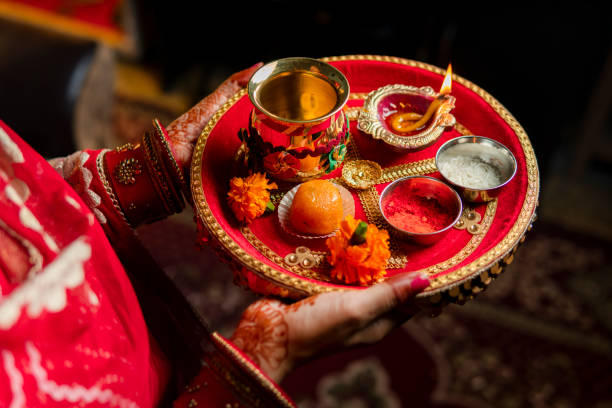 Tradition Indian woman holding a plate decorated with oil lamp, sweet food, flowers, and religious offering on the occasion of Karwa Chauth festival. Tradition Indian woman holding a plate decorated with oil lamp, sweet food, flowers, and religious offering on the occasion of Karwa Chauth festival. diwali jwellery stock pictures, royalty-free photos & images