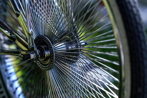 Shiny chrome bicycle spokes on a stylish wheel, closeup detail.