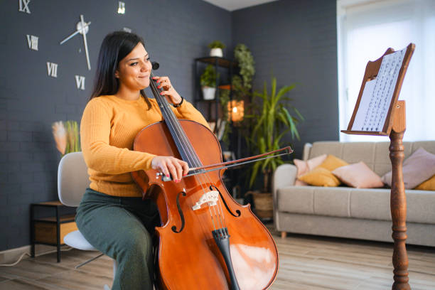 istock Young woman playing violoncello at home 1428763043