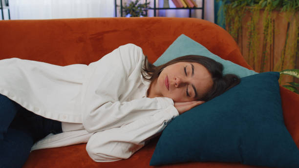 istock Tired young woman lying down in bed taking a rest at home, napping, falling asleep on orange couch 1428765606