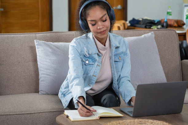 istock African woman, American, using laptop computer and wearing headphones for online learning. 1428768232