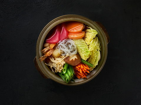 Asian or japanese style soup with noodles,tuna,salmon, mushrooms and green onions close-up in a bowl on the table. Horizontal top view from above