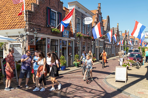 Edam, Netherlands, August 10, 2022; Cozy narrow street with Dutch flags in the center of the picturesque Dutch cheese town of Edam.