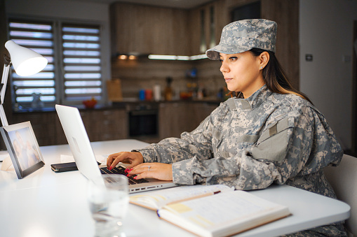 Female soldier working on laptop at home