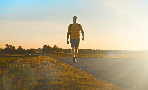 istock Man with backpack walks along the road on the sunset. 1428774045