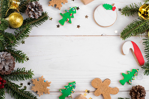 Christmas frame background with Christmas gingerbread cookies, fir branch and festive decoration on white wooden background. Christmas background above, flat lay, copy space