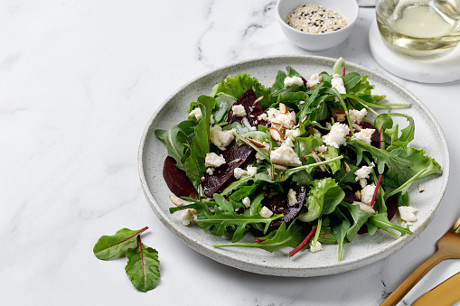 Healthy vegetarian salad with beet, mix salad leaves, feta cheese, nuts. Meal healthy snack copy space for text. On marble white background.