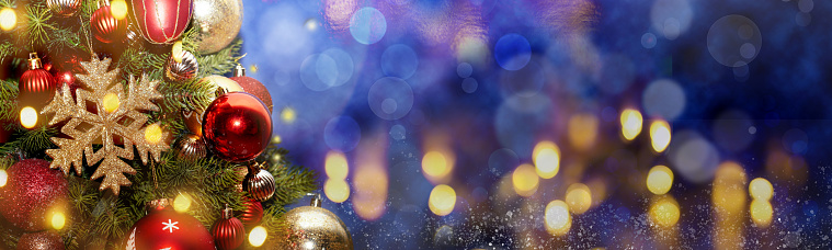 Christmas fir tree background with baubles, snowflake and glowing Christmas lights bokeh