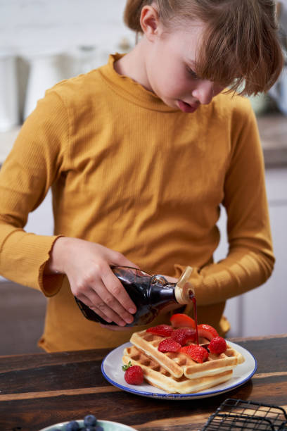 istock Young Girl Preparing Waffles with Fresh Berries in Domestic Kitchen 1428783356