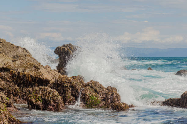 ocean waves crash against the rock stock photo