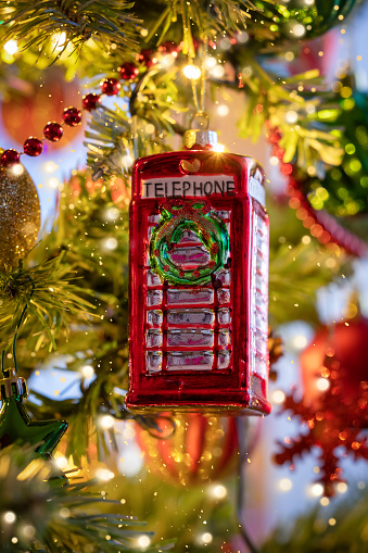 A classic, british, red telephone booth from England as a christmas ornament on a illuminated tree with selective focus