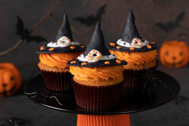 istock Halloween cupcakes decorated witch hat from mastic on brown background with spiders and bats, sweets for kids on Halloween party 1428790729