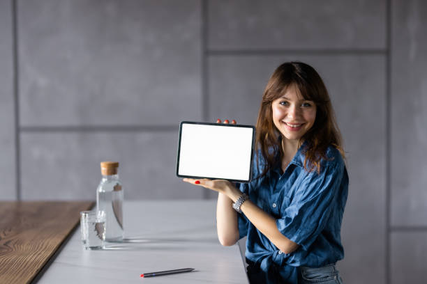 istock Young pretty woman using tablet holding white screen at home 1428792577