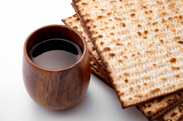 rituel religieux juif, fête de la pâque hébraïque et concept du judaïsme avec pile de beaucoup de pain casher sans levain (matzo) et une tasse de vin en bois isolée sur fond blanc - unleavened bread photos et images de collection