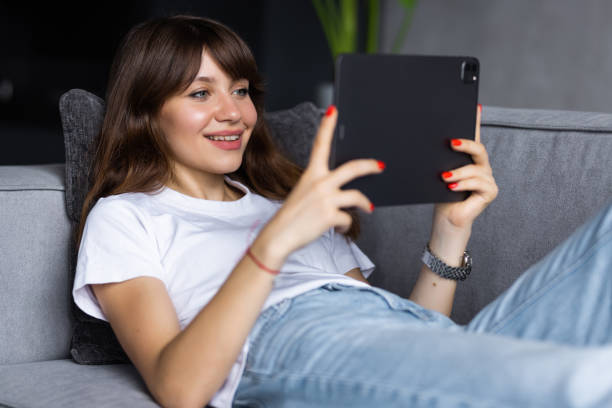 istock Young woman using tablet sitting on sofa at home at living room 1428794213