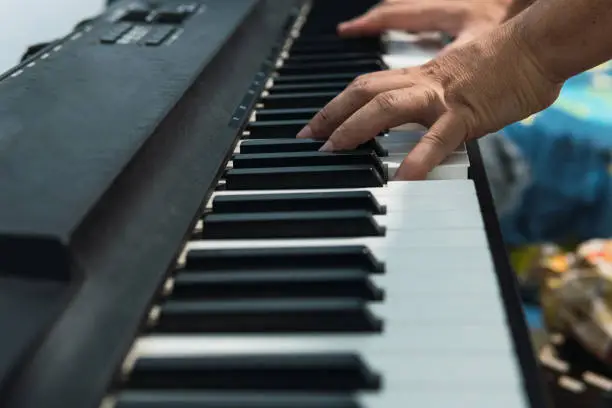 Photo of Image of the hands of an unrecognizable person playing the keys of the electronic digital piano.