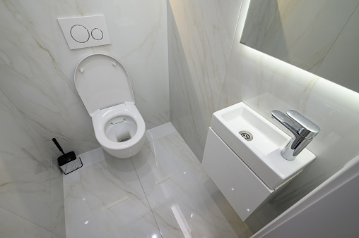 Small toilet bathroom interior with hand wash sink and toilet bowl