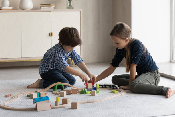 istock Two focused kids building toy railroad on floor, completing construction 1428799712