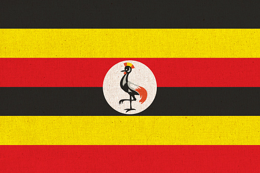 Flag of Uganda. Ugandan flag on fabric surface. Fabric texture. National symbol of Uganda on patterned background. Republic of Uganda