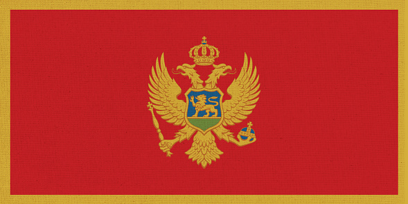 Flag of Montenegro. Montenegro flag on fabric surface. Fabric texture. National symbol of Montenegro on patterned background. Europian Country