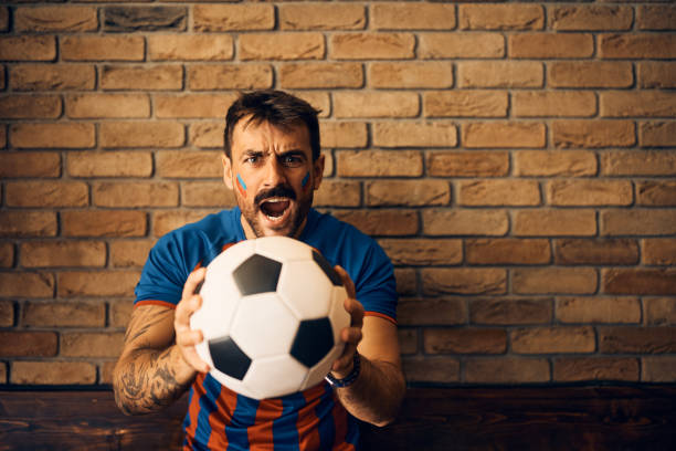 istock Excited soccer fan cheering during the world cup and looking at camera. 1428803511