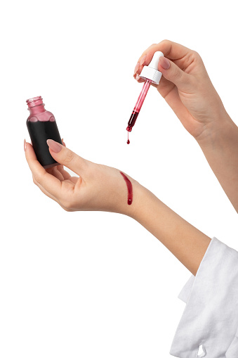 Woman holding pipette and applying skin red serum peeling aha bha acids to her hands to her female hands on a white isolated background. Female skin care
