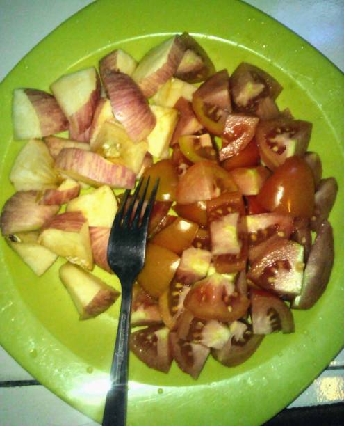 istock Sliced apples and tomatoes on a green plastic plate, for a healthy breakfast 1428811610