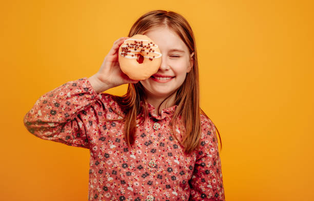 Girl with donut isolated on yellow background