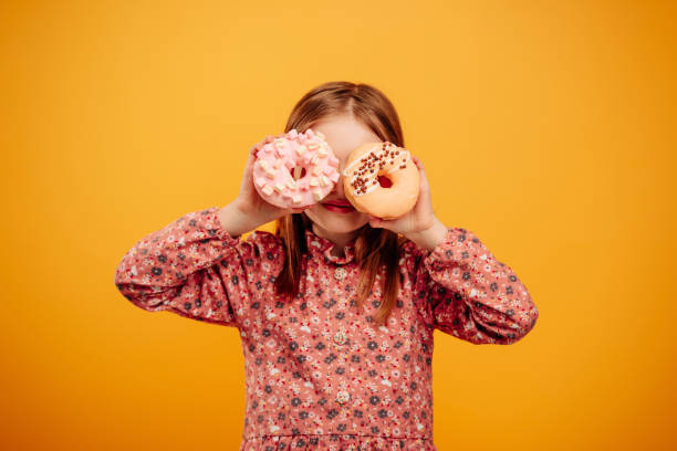 istock Girl with donuts isolated on yellow background 1428812536