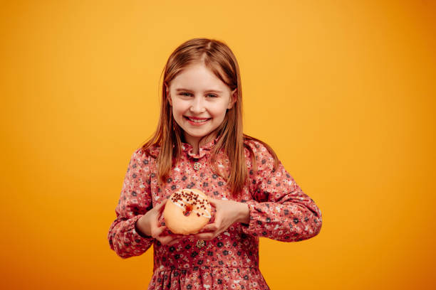 Girl with donut isolated on yellow background
