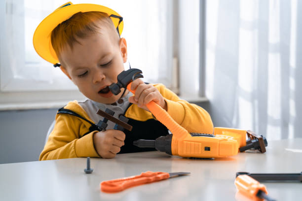 istock Child play with work tools at home, dreams to be an engineer. Little boy builder. Education, and imagination, purposefulness concept. Kid and hummer 1428813448