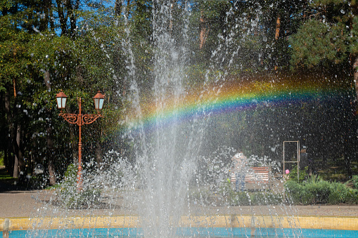 Rainbow in the jets and splashes of the fountain on a sunny day