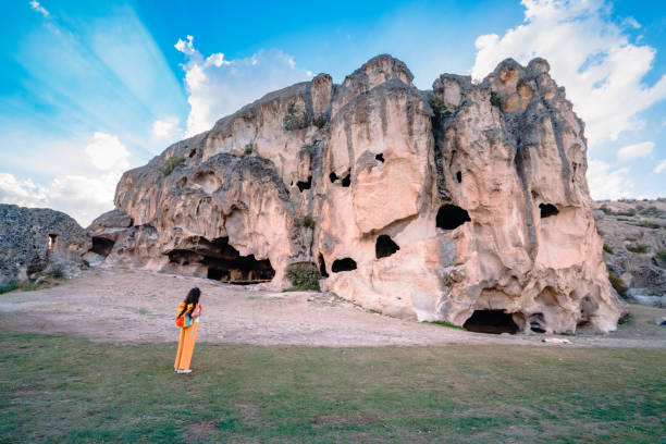 piękna kobieta podróżnik ogląda pierwszą na świecie jaskinię apartamentową w historii, w starożytnych ruinach miasta ayazini w dolinie frygii, turcja - civilization zdjęcia i obrazy z banku zdjęć