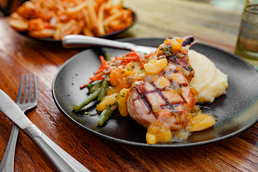 juicy delicious roast chicken legs with green beans, lemon, fried tomatoes and fresh basil on plate on white  textured wooden table