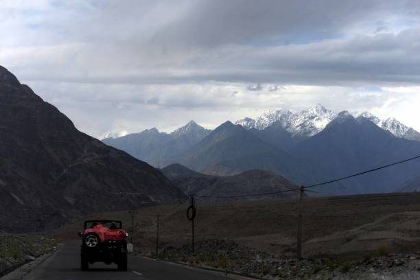 Jeep on their destination at kkh highway pakistan The Karakoram Highway is a 1,300 km national highway which extends from Hasan Abdal in the Punjab province of Pakistan to the Khunjerab Pass in Gilgit-Baltistan, where it crosses into China and becomes China National Highway 314. karakoram highway stock pictures, royalty-free photos & images