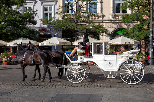 Cracow, Poland - September 1, 2022: Tourists driving in a carriage around Cracow, Market Square, Poland.